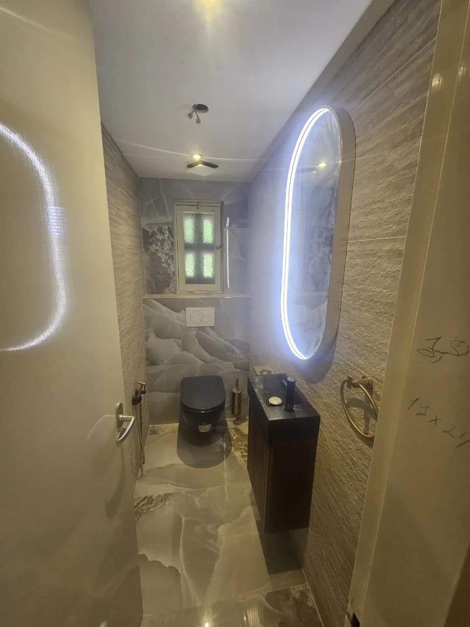 Toilet with oval illuminated mirror and decorative wall tile