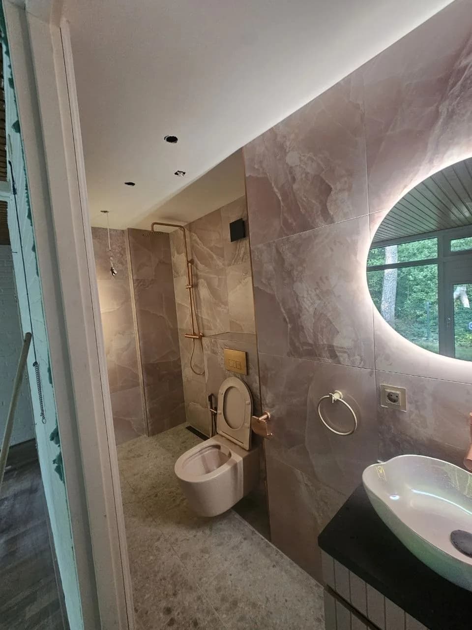 Toilet and walk-in shower with pink stone-look tiles