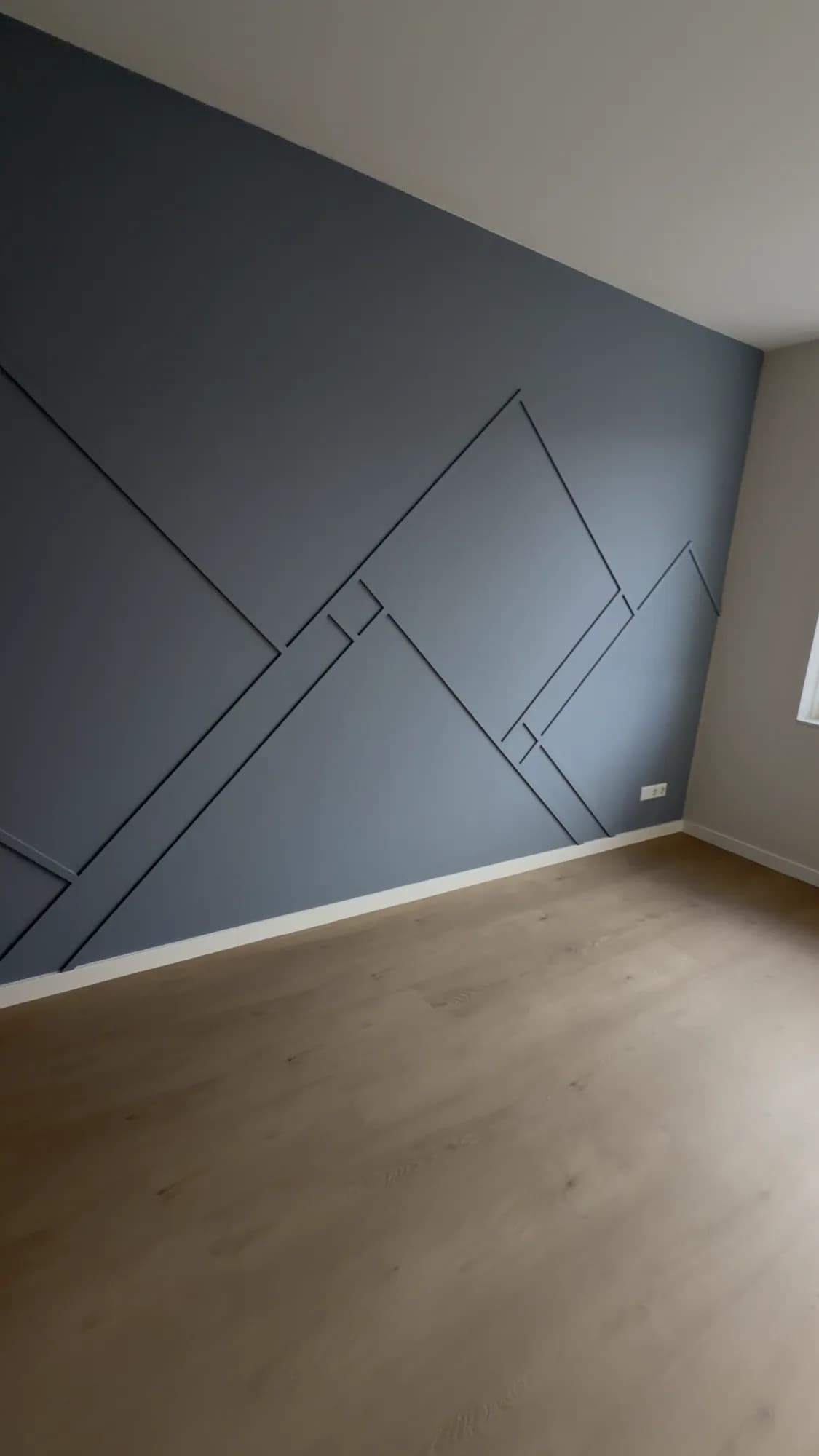 Grafische accentwand in donkergrijs met laminaatvloer