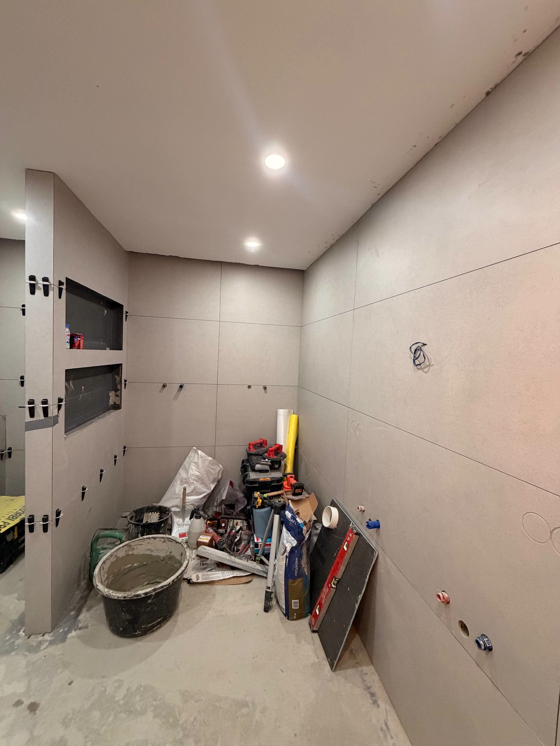 Badkamer tijdens de verbouwing met grootformaat wandtegels en twee ingebouwde nissen.
