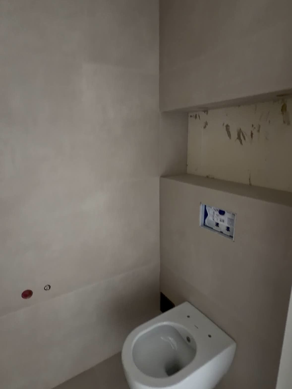 Toiletruimte met glad afgewerkt stucwerk, een hangend toilet en een inbouwreservoir.